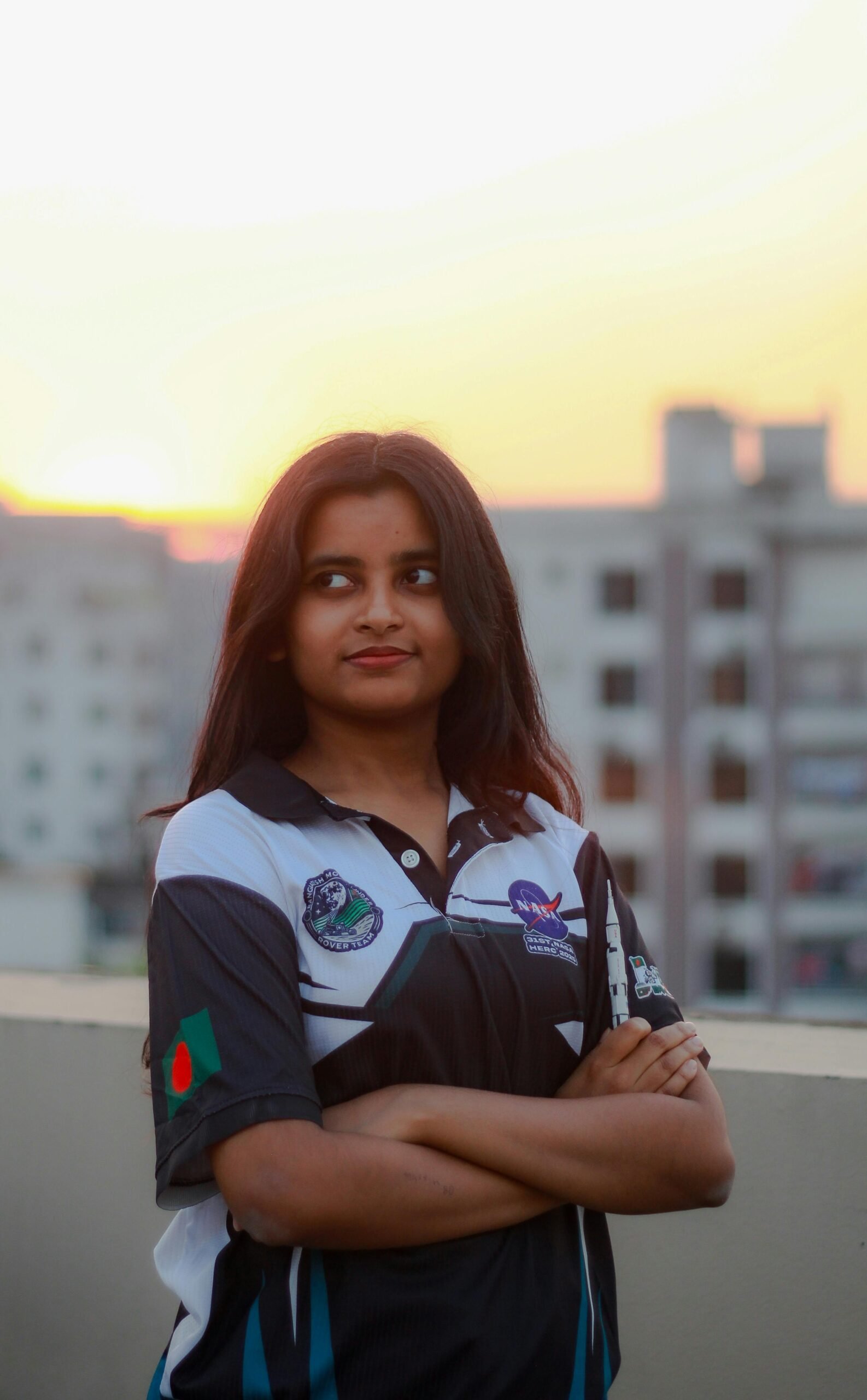 Portrait of a young woman in Dhaka, Bangladesh wearing a robotics-themed shirt at sunset.